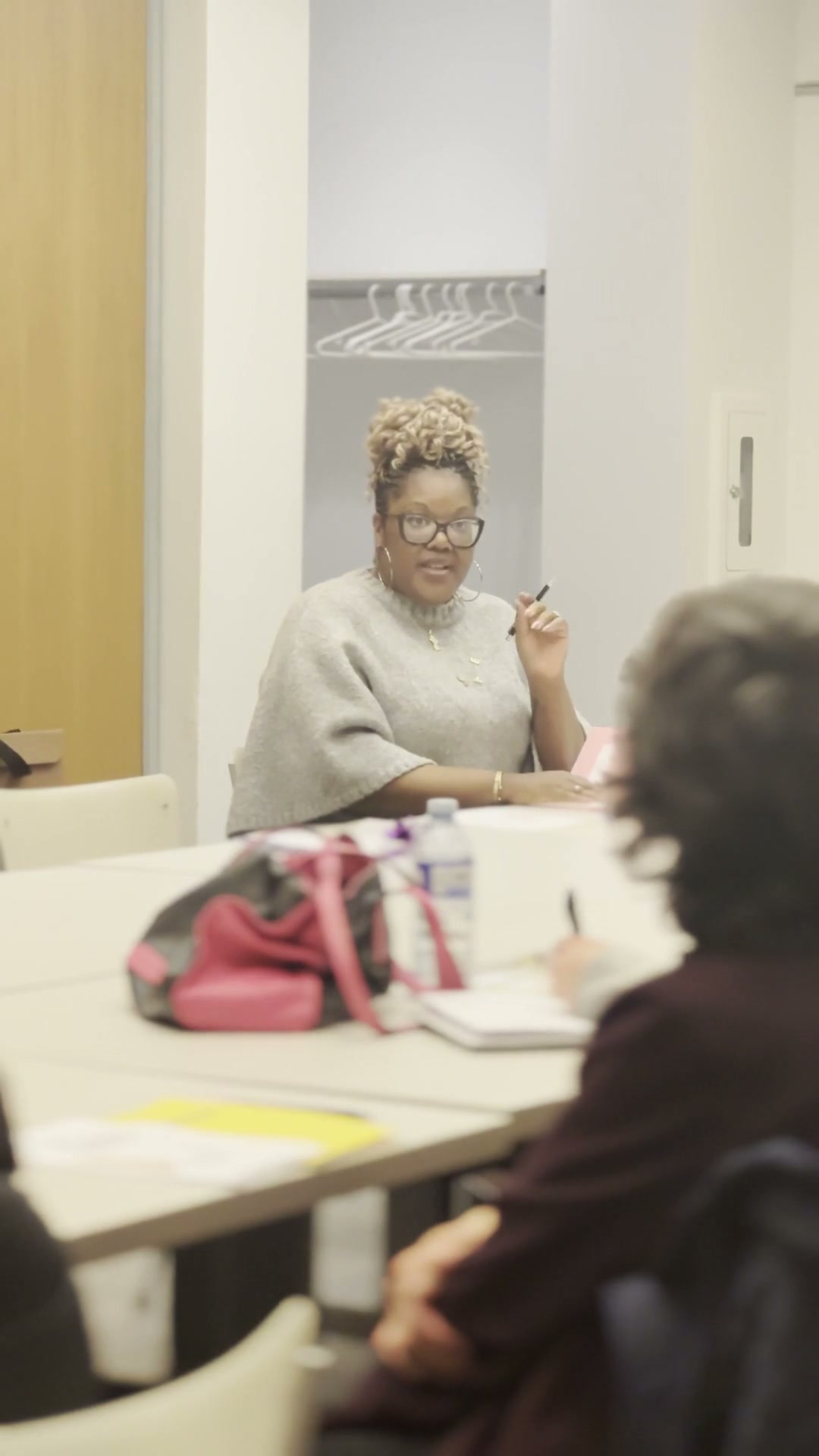 Onika Dainty seated at a table while facilitating a community workshop, with a participant in the foreground